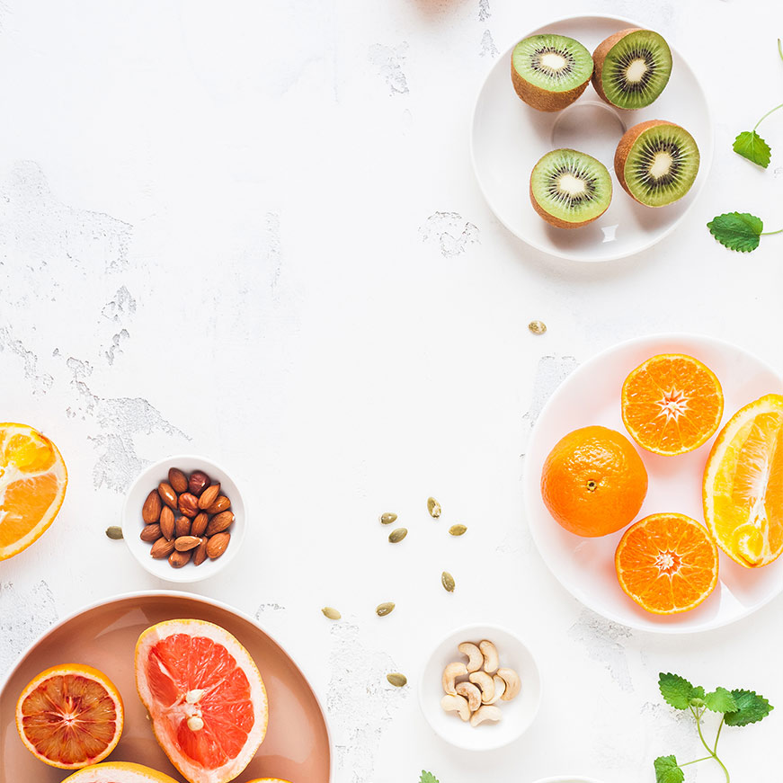 Kiwis, oranges and nuts in bowls
