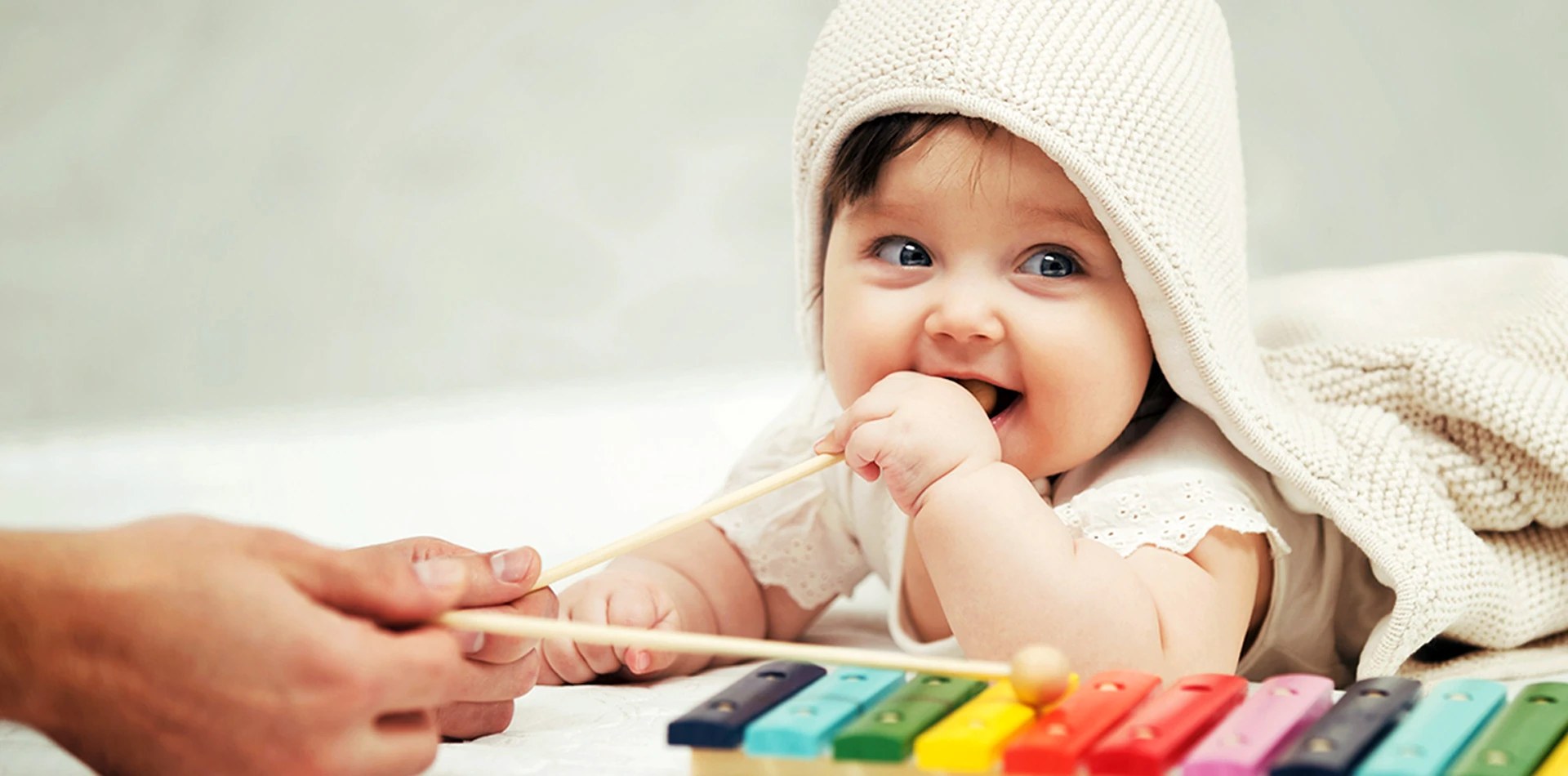 Baby playing a toy xylophone with a parent