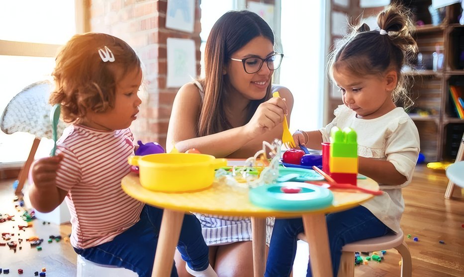 Teacher with toddlers at a play table