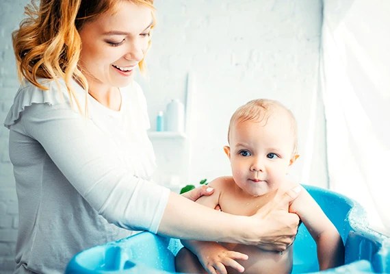 Mother bathing her baby in a blue tub