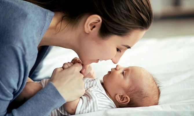 Mother kissing her baby on the bed