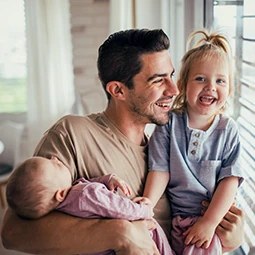 Father cuddling a baby and a toddler