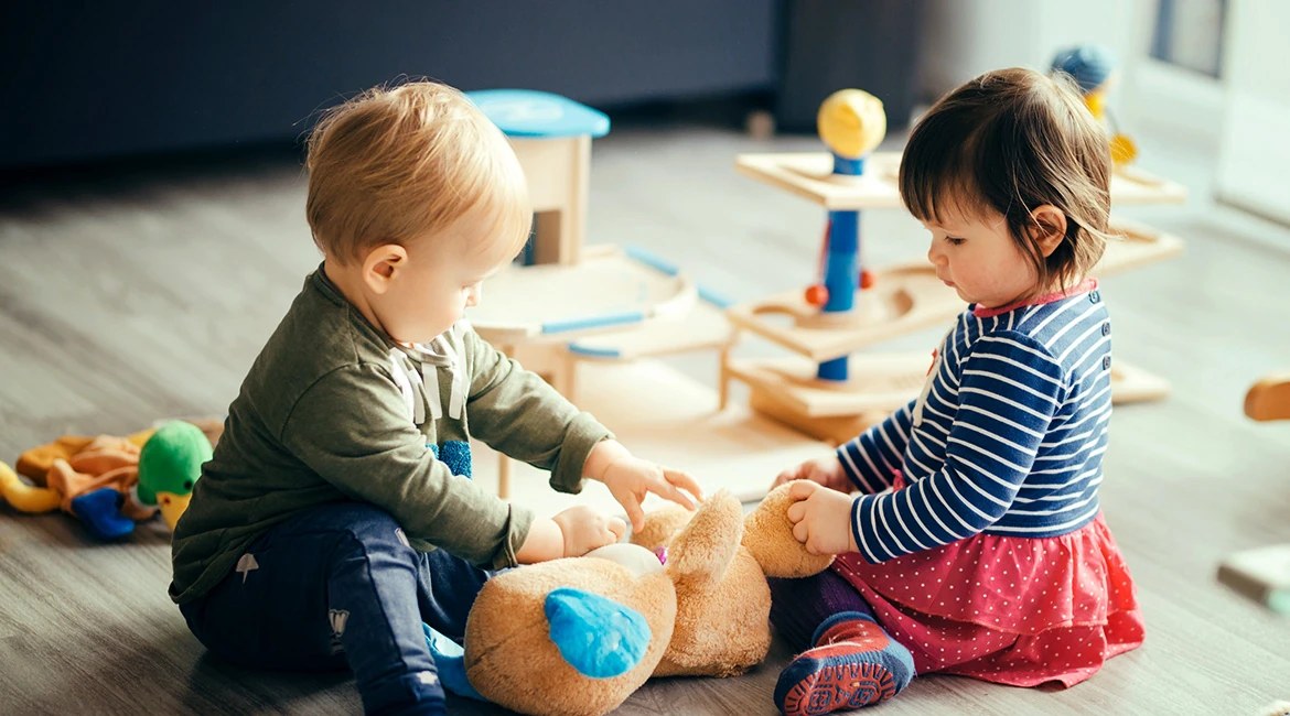 Two toddlers playing together with wooden toys