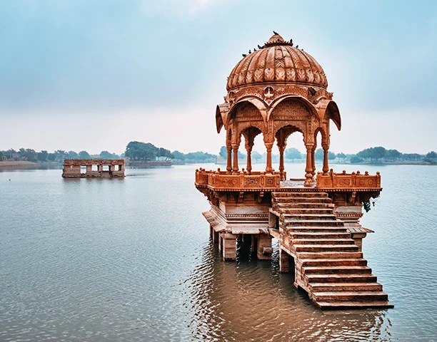 A carved sandstone pavilion standing in Gadisar Lake at Jaisalmer