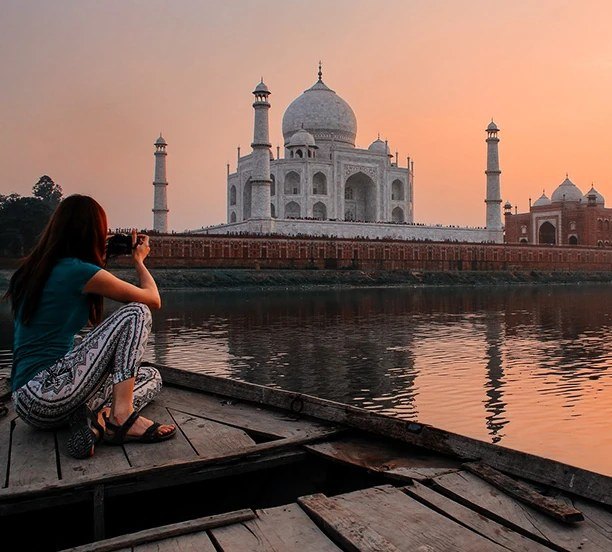 A traveller photographing the Taj Mahal from a boat on the Yamuna
