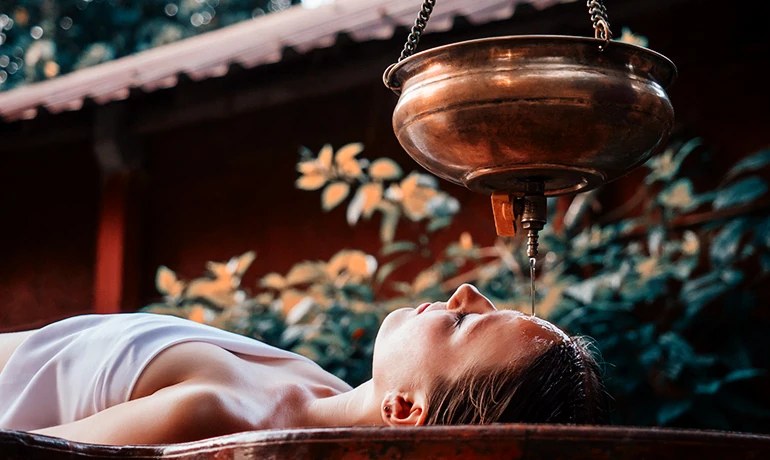 Warm oil poured onto a guest&rsquo;s forehead during a shirodhara treatment