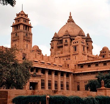 The domes of a red sandstone palace under a blue sky