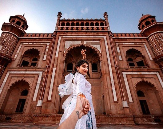 A traveller standing in a red sandstone gateway