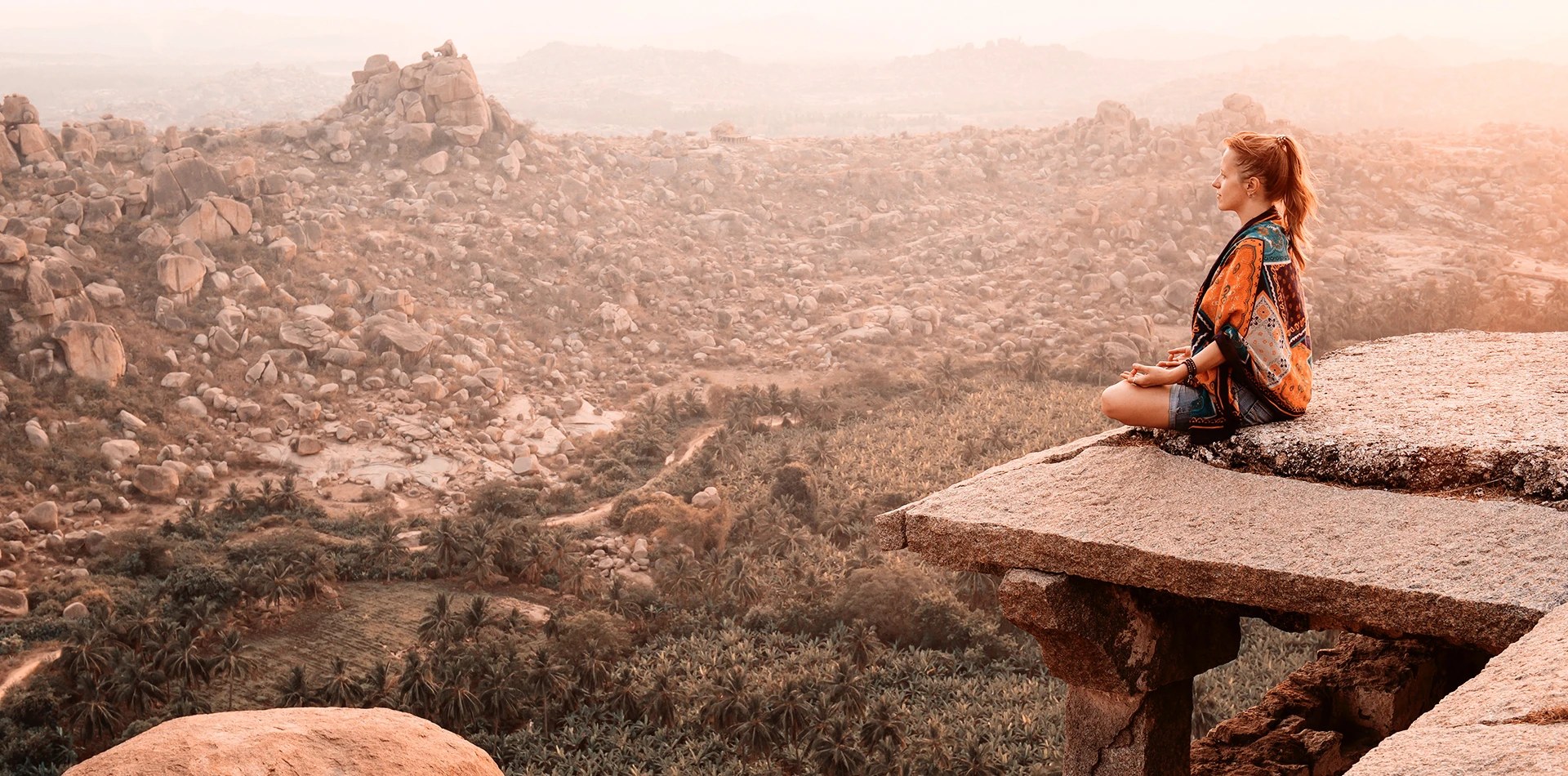A traveller resting on sandstone boulders above a valley