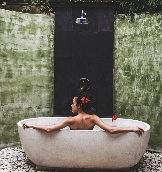 An open-air stone bath under a rain shower