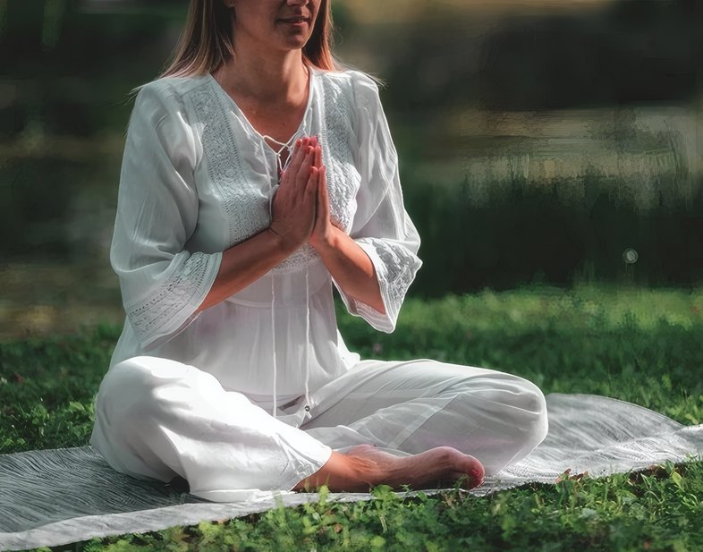 A guest meditating on the lawn in white linen
