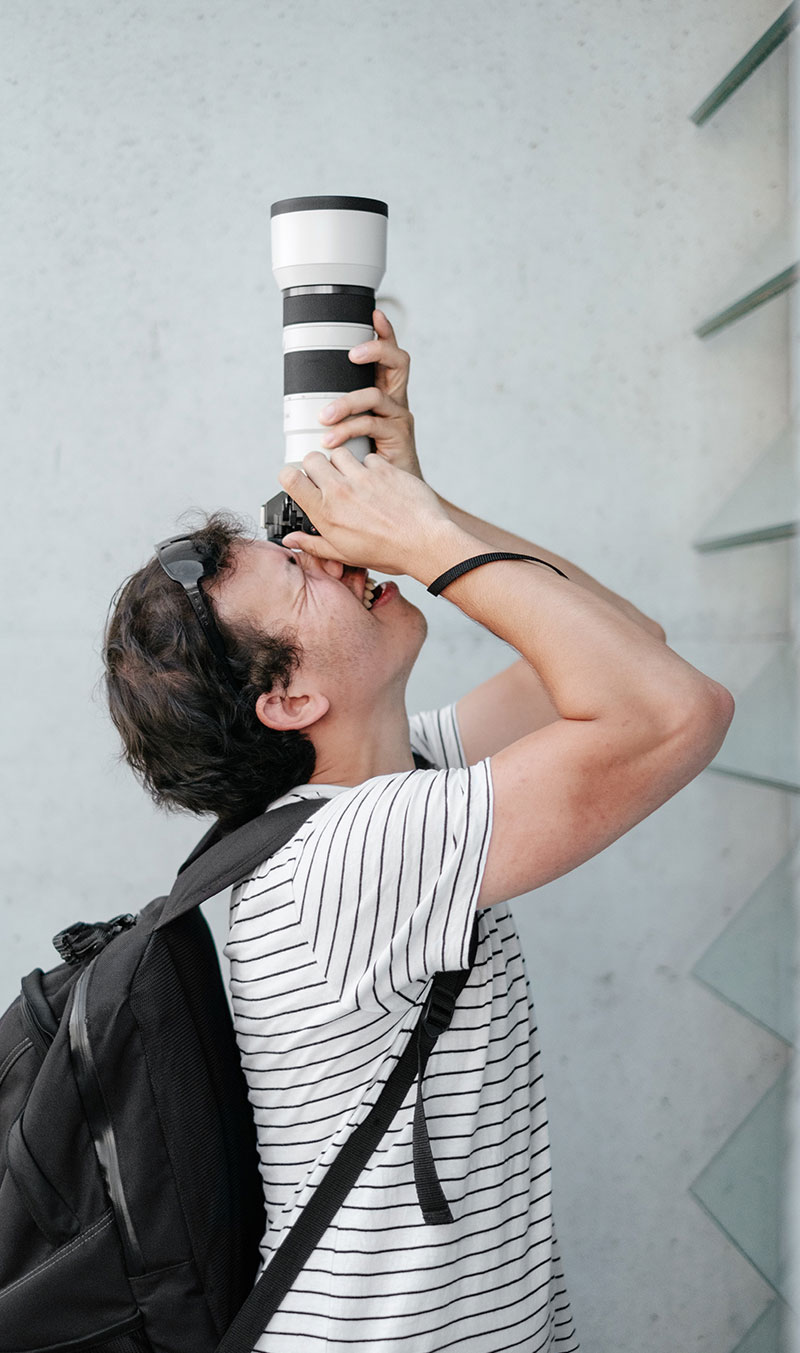 A photographer aiming a long lens upwards