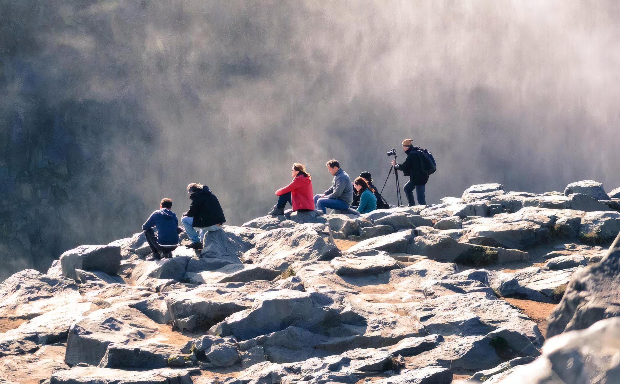 A workshop group with tripods on the rocks above the sea