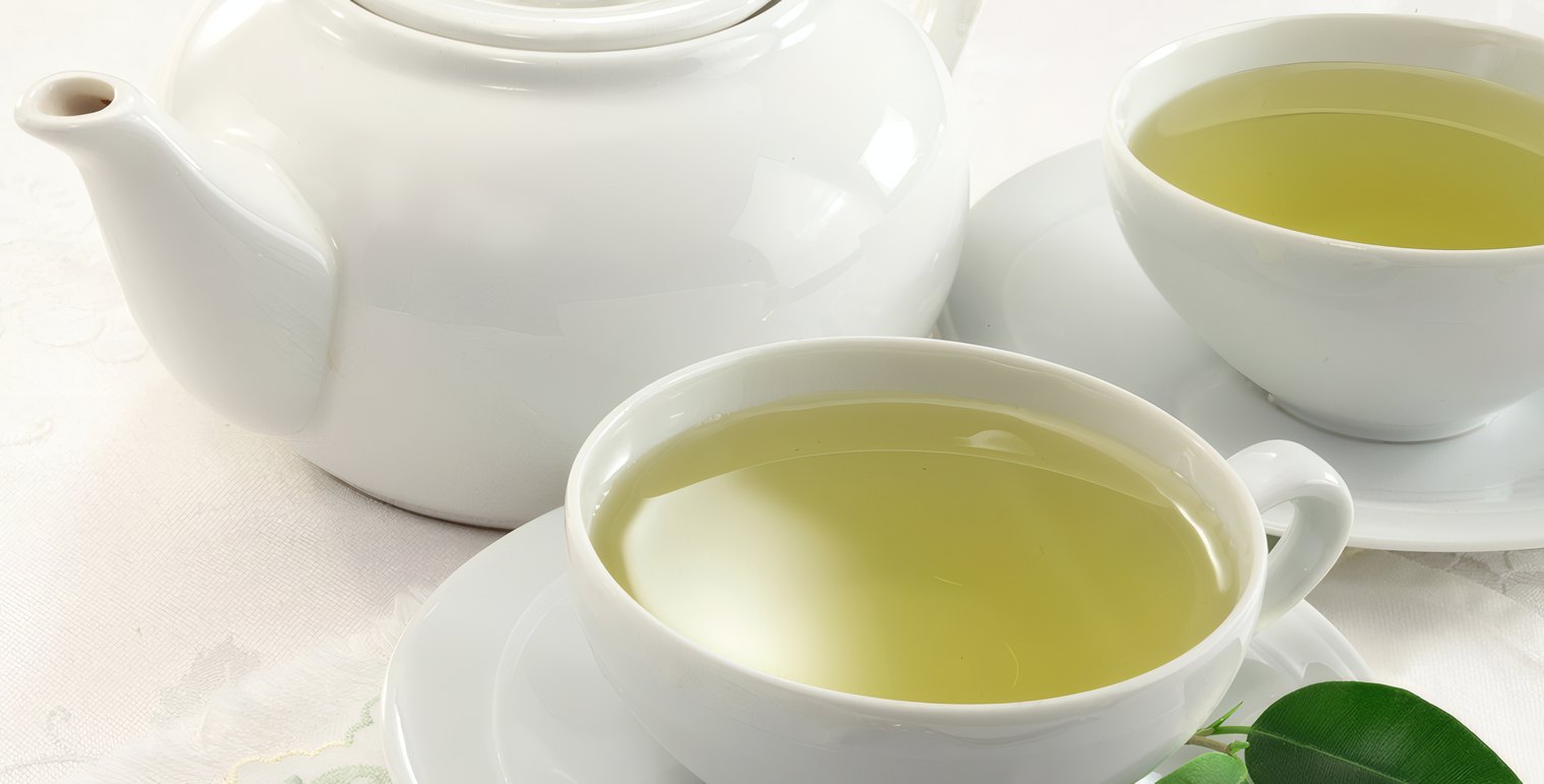 A white teapot and a cup of green tea