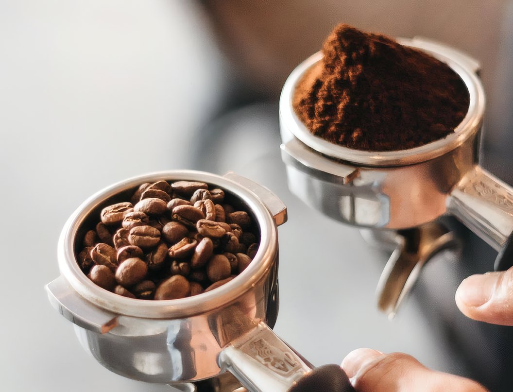 Fresh beans beside a portafilter of ground coffee
