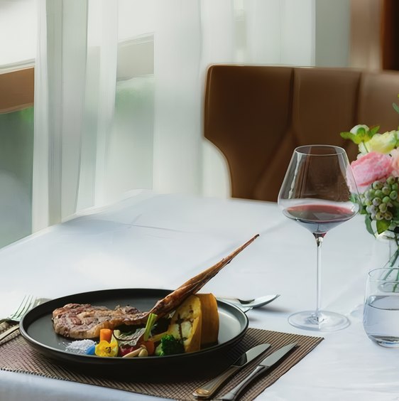 A plated lamb dish with a glass of red