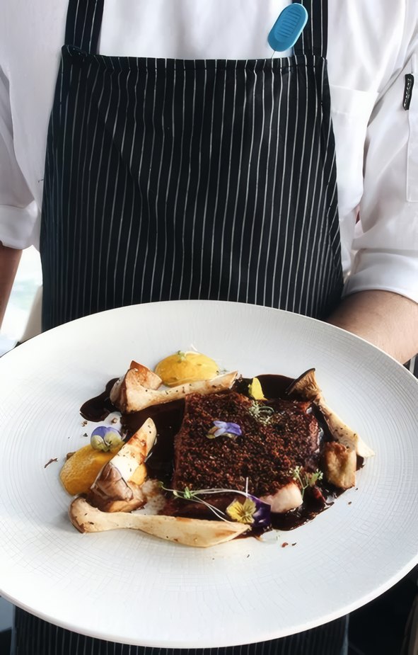 A plate of beef with mushrooms held at the pass