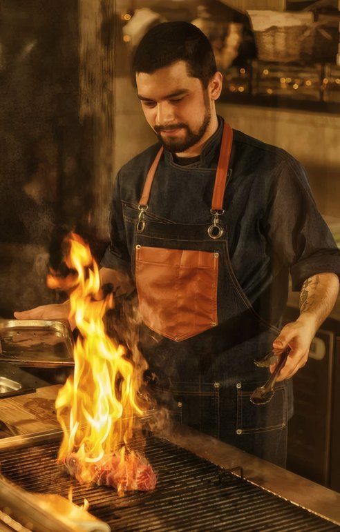 A cook at the open fire of the grill