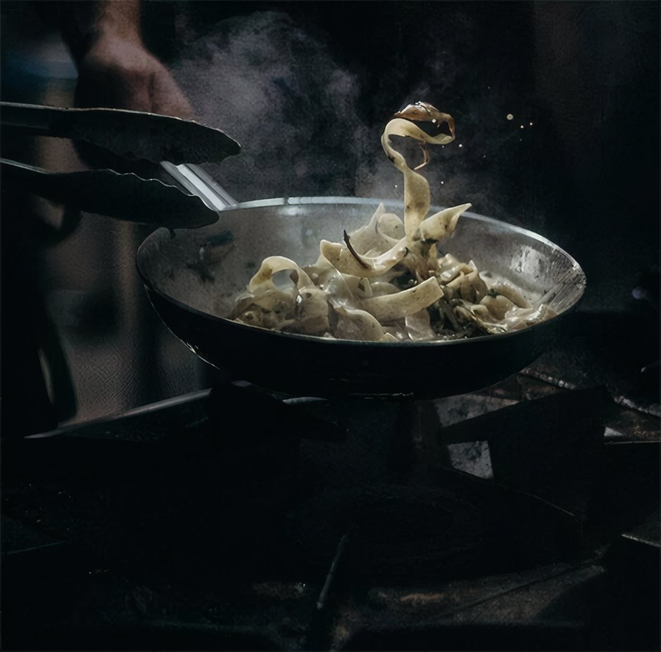 Pasta tossed in a pan over the flame