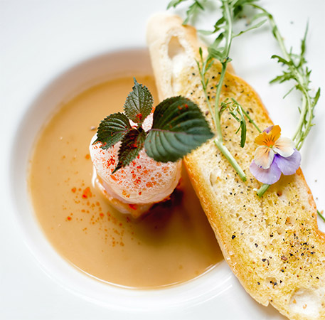 A bowl of soup with toasted bread and herbs