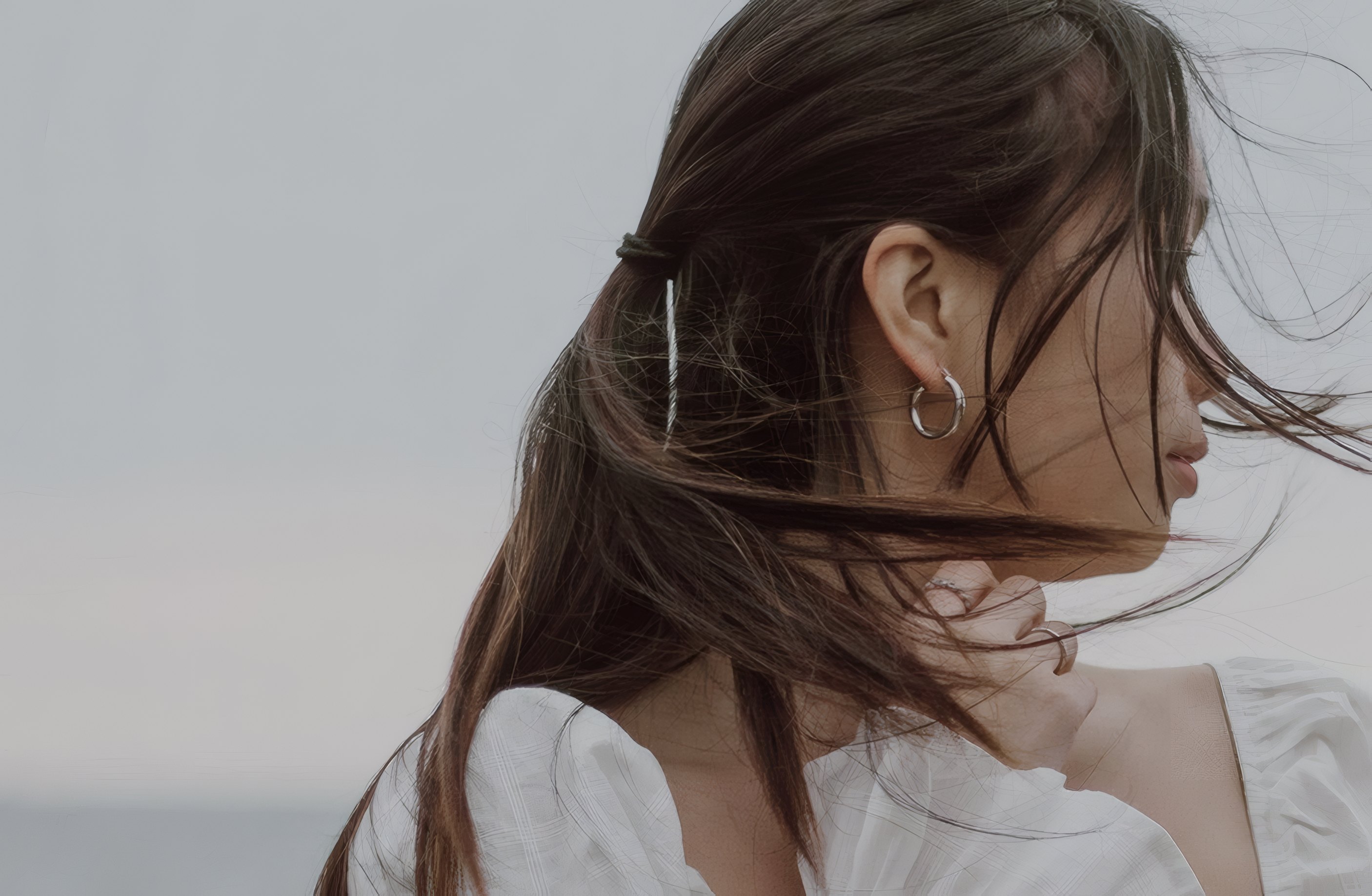 A model's hair caught in the wind, a silver earring
