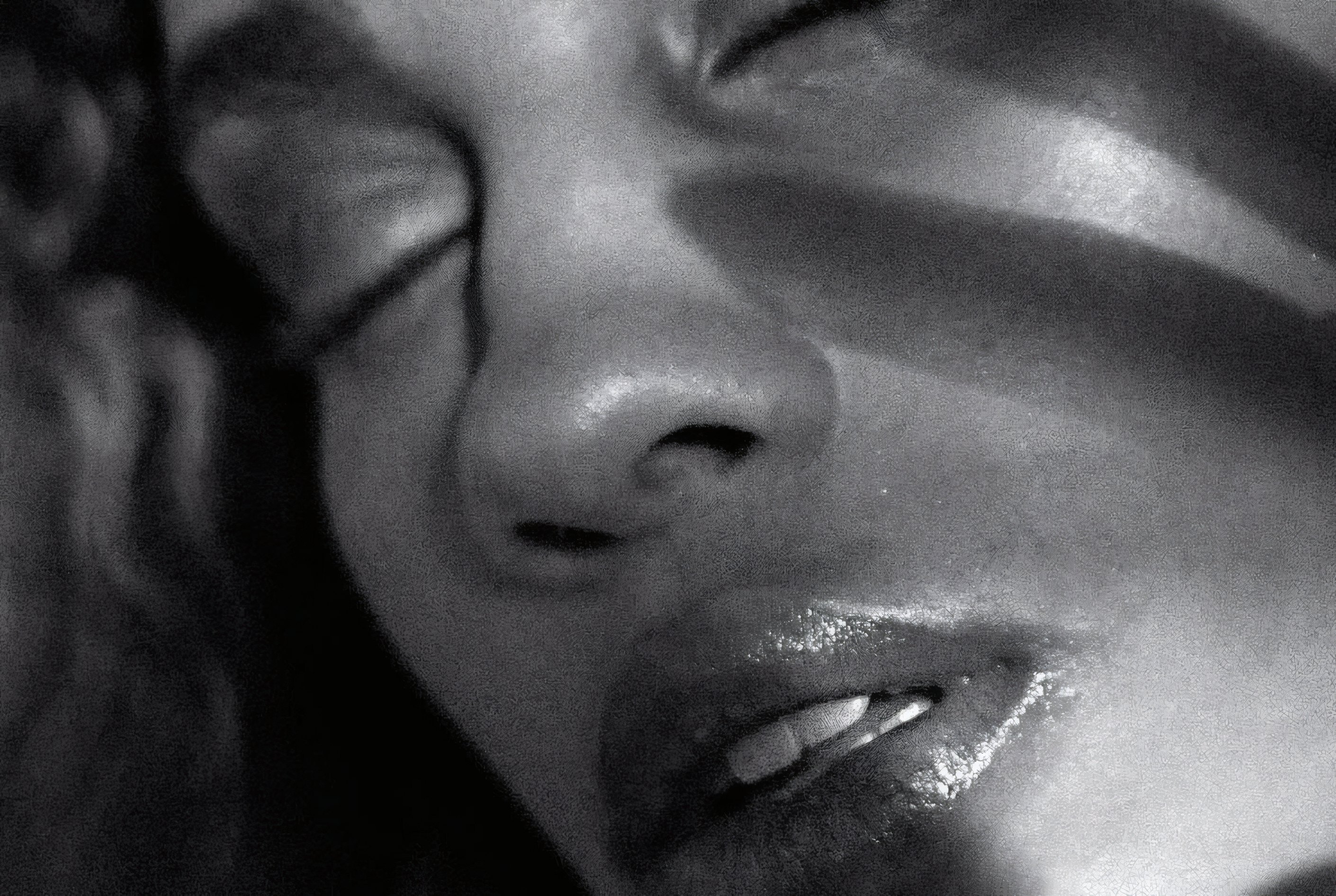 A face crossed by a stripe of light, in black and white