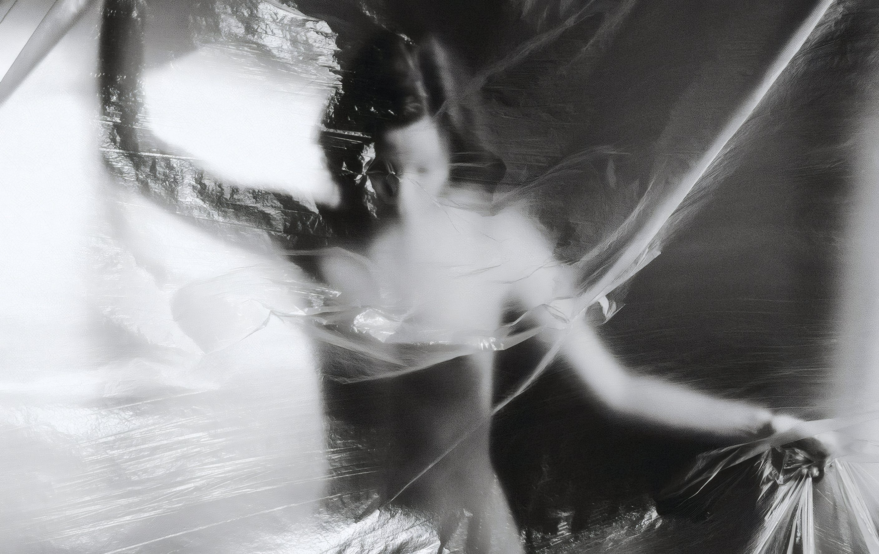 A dancer wrapped in a clear veil, in black and white