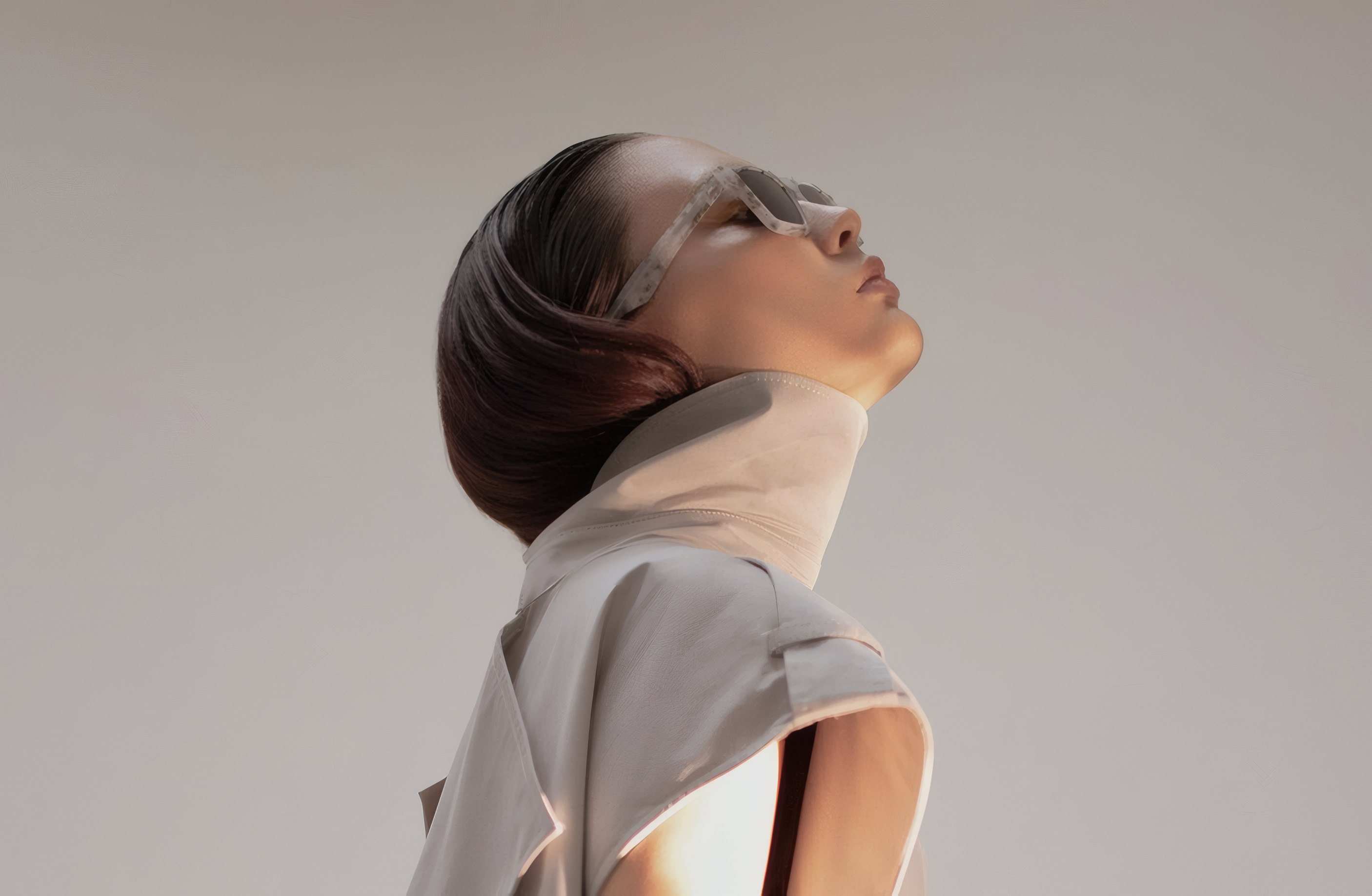 A model in a beige trench looking up into the light