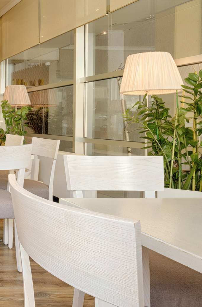 A white dining room with a tall window and a lamp