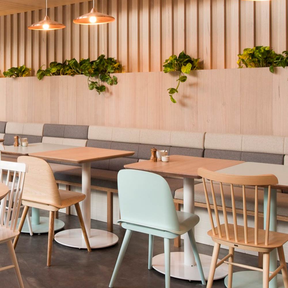 Wooden tables and mint chairs under copper lamps