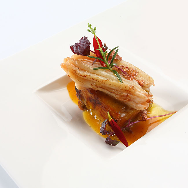 A glazed fish fillet on puff pastry with a red sauce