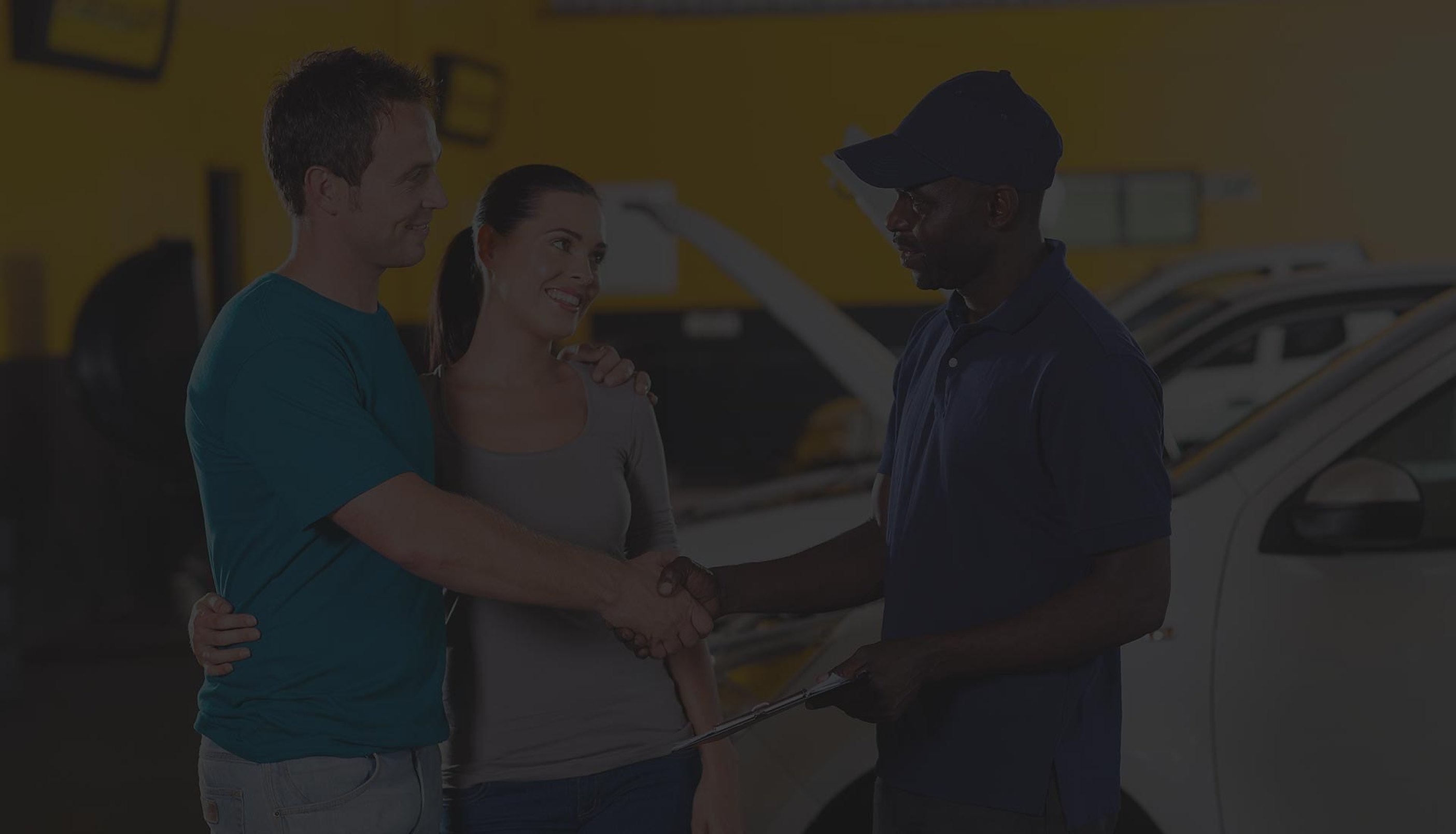 A mechanic shaking hands with a couple
