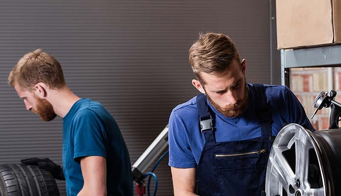 Two mechanics fitting an alloy wheel