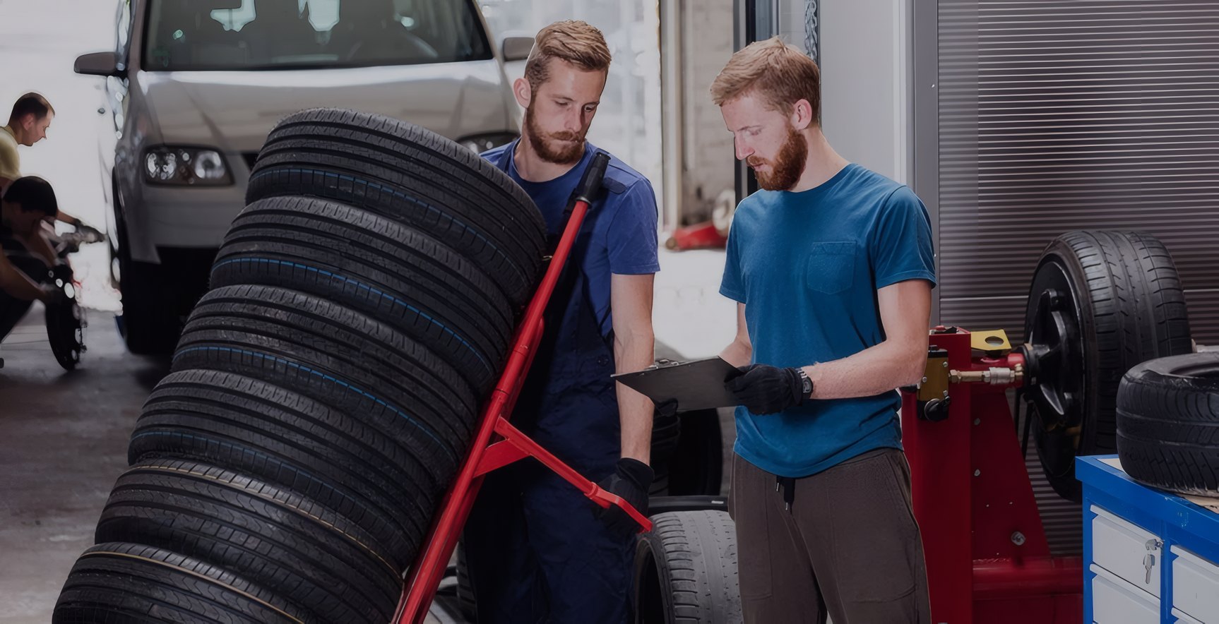 Two mechanics moving tyres on a trolley