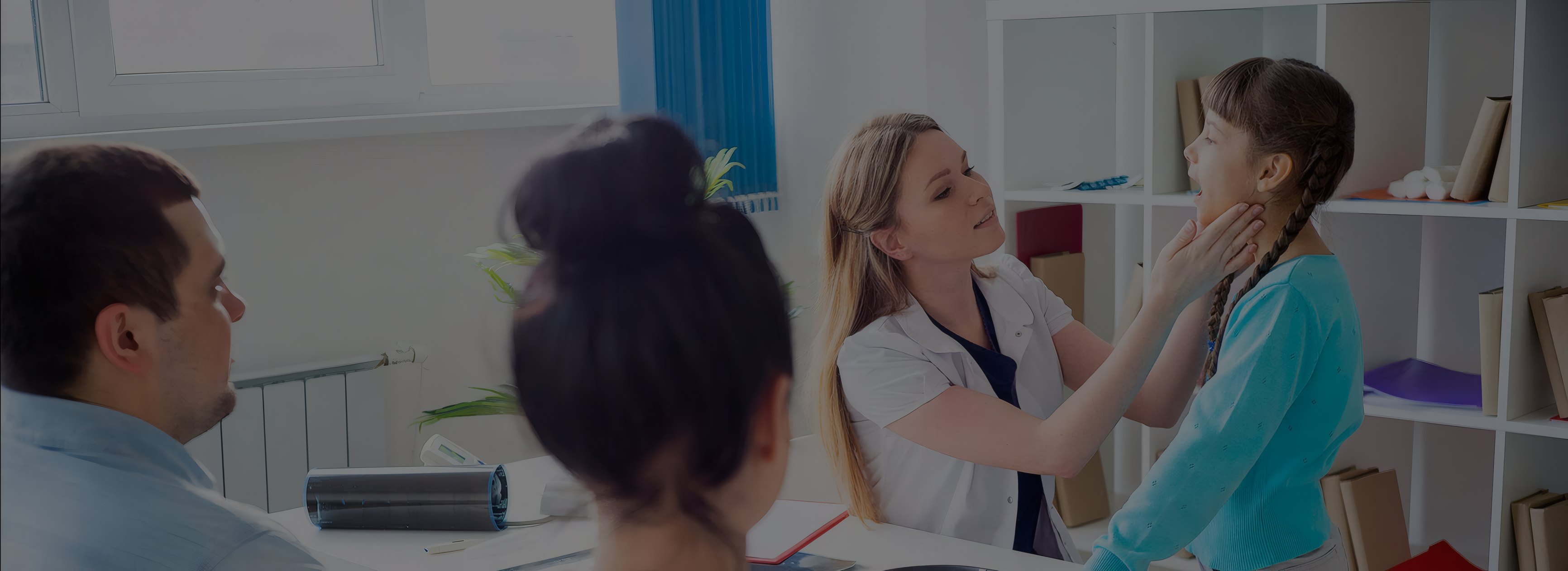 A pediatrician checking a girl's throat with her parents beside her
