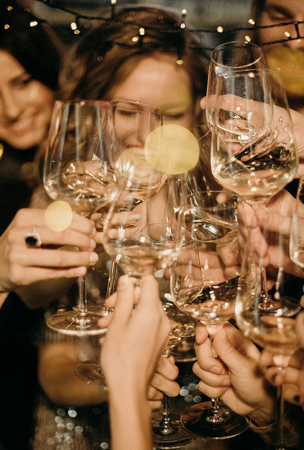 Friends raising wine glasses under fairy lights