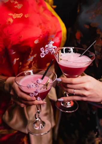 Two pink martinis held up in a crowd