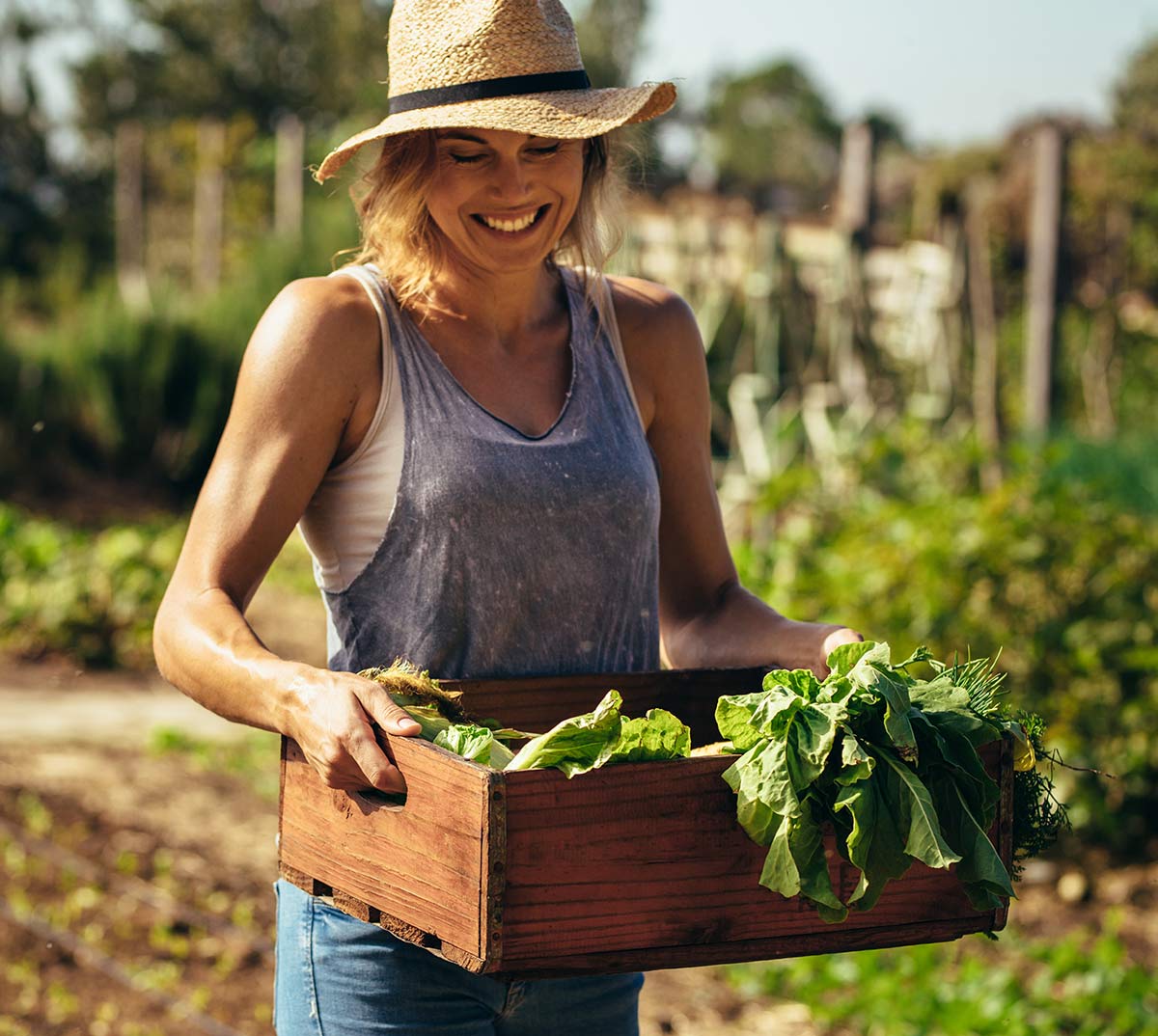 A grower carrying a crate of greens