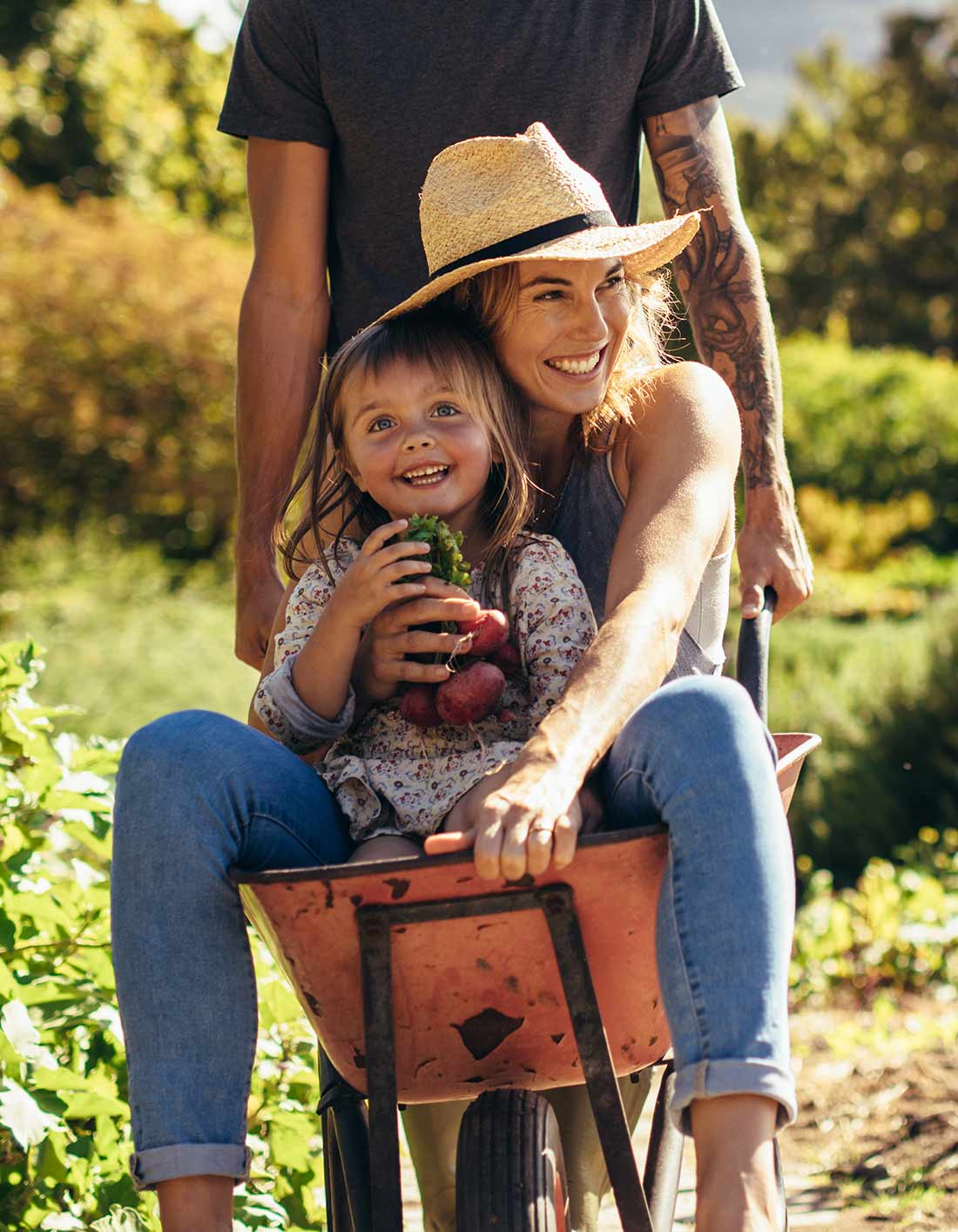 A father and daughter with a wheelbarrow of produce