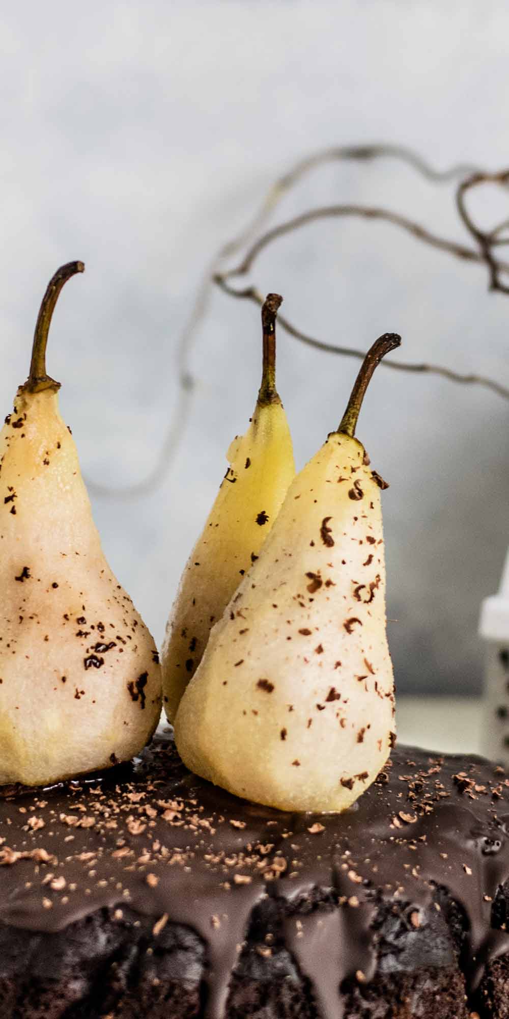 Poached pears standing on a chocolate cake