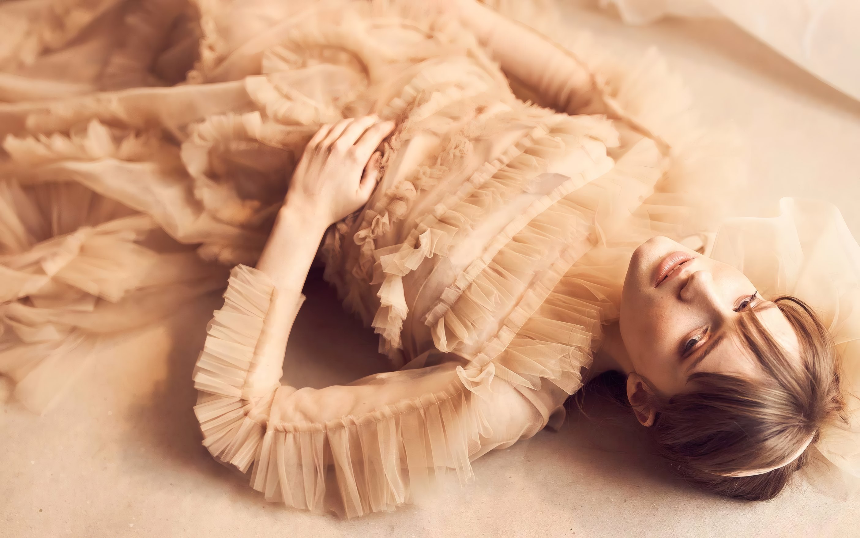 A child in a peach tulle dress lying on soft fabric
