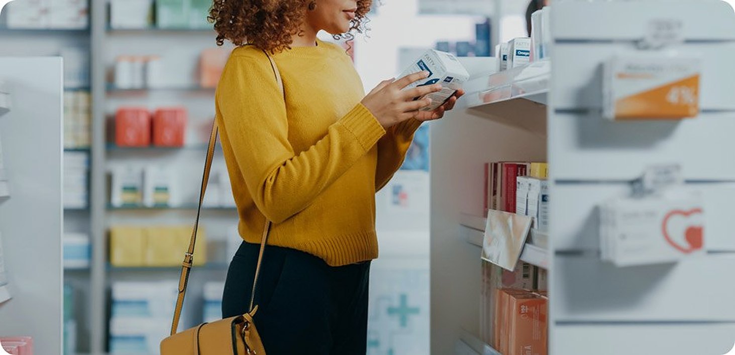A customer reading a label at the pharmacy shelves