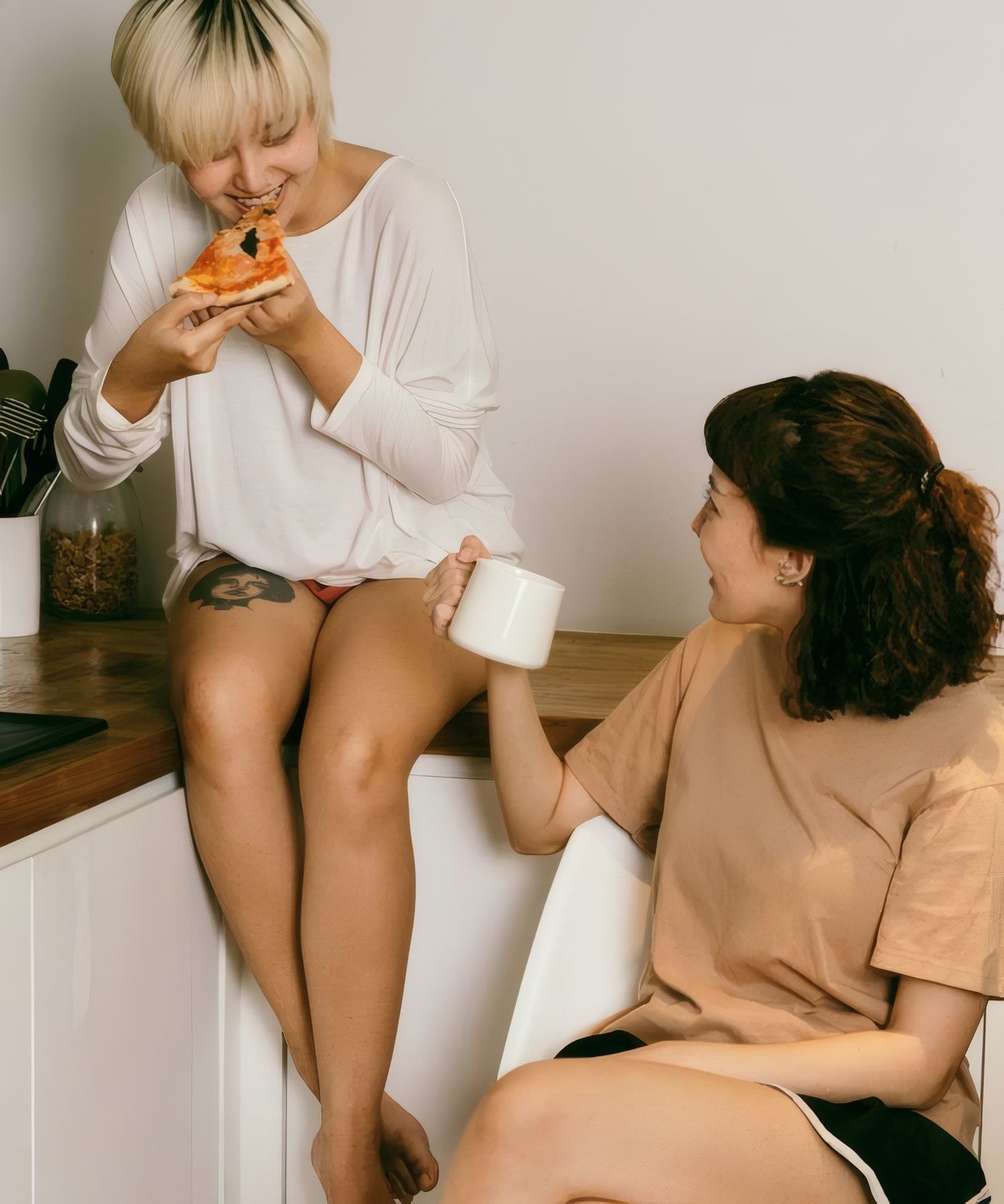 Two friends sharing pizza in a kitchen