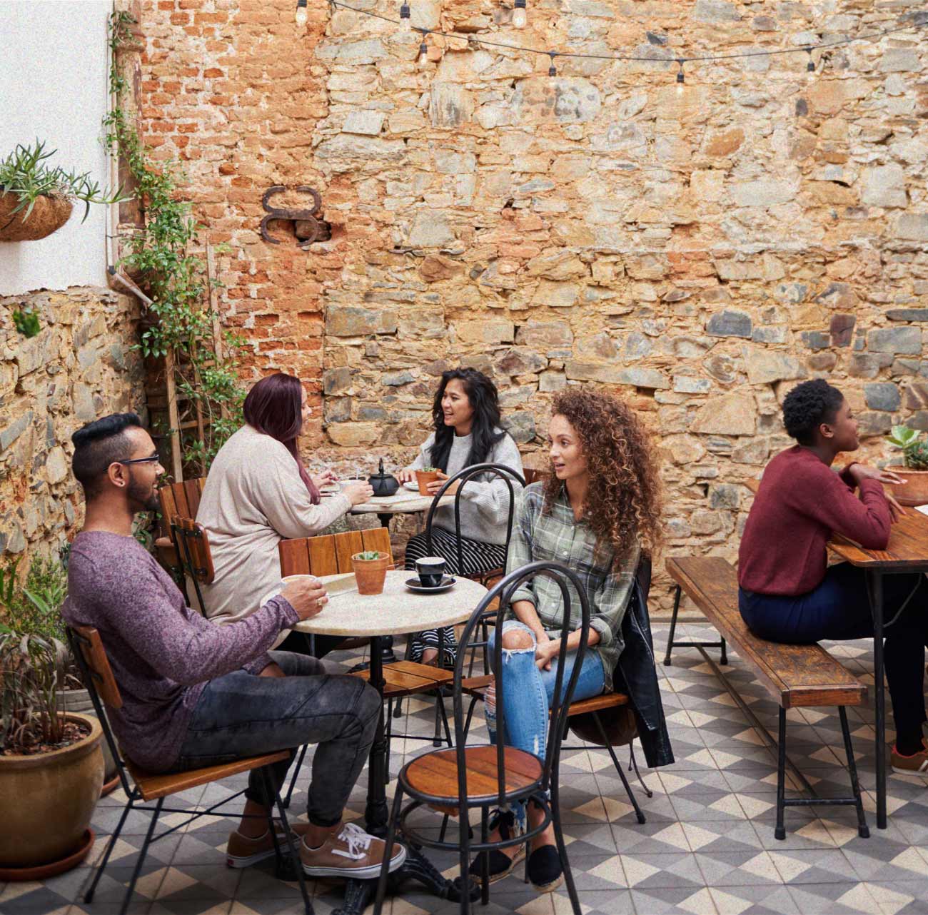 Friends at long tables in a sunny courtyard