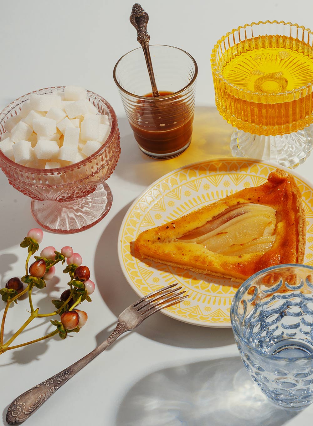 A pear tart and glassware on a breakfast table