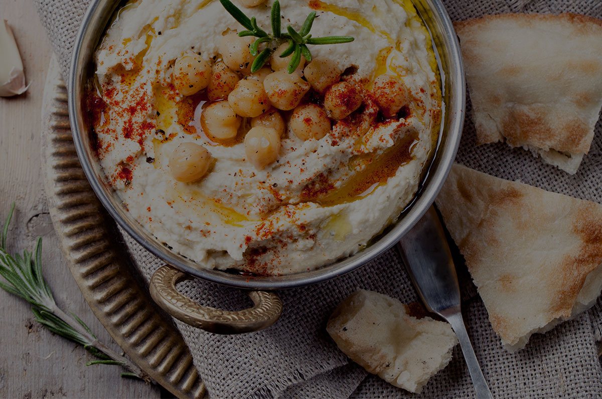 A bowl of hummus with chickpeas, olive oil and flatbread