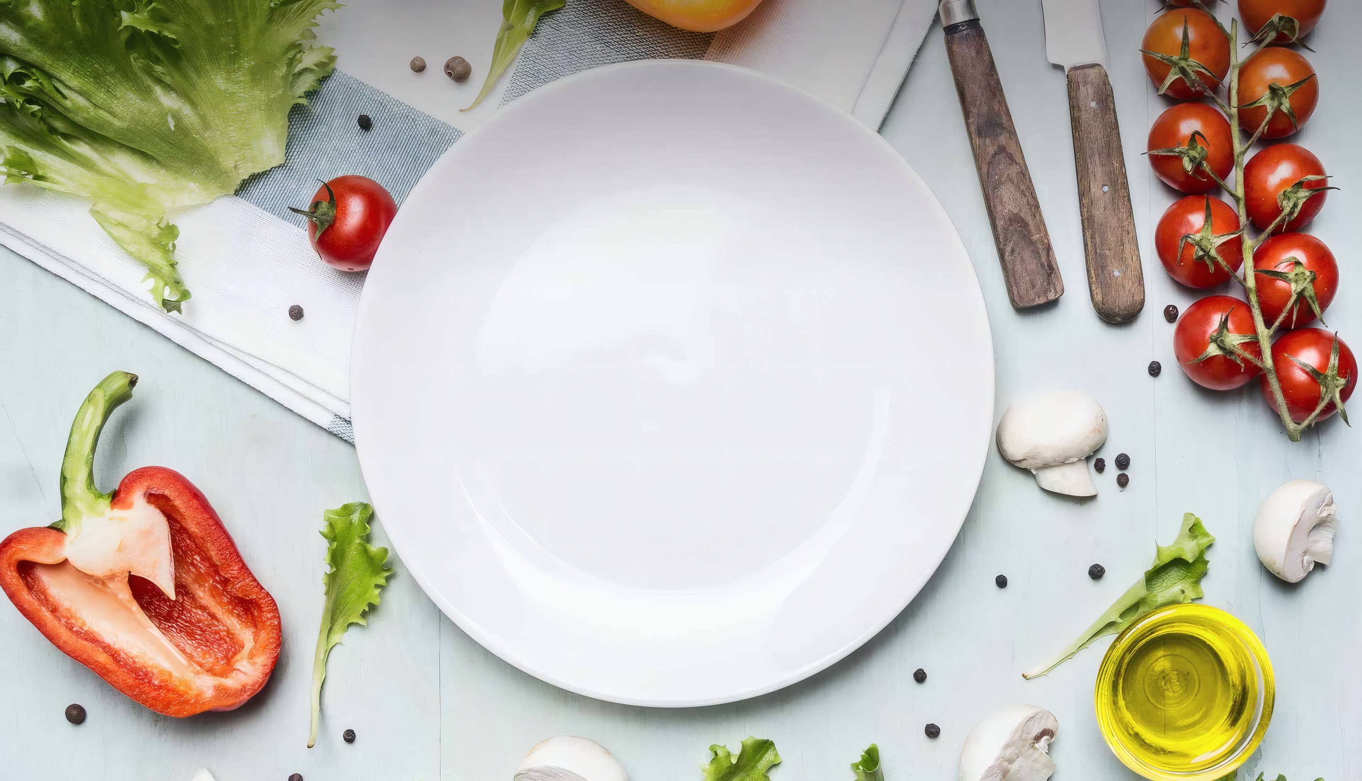 Tomatoes, peppers, lettuce and olive oil laid round a white plate