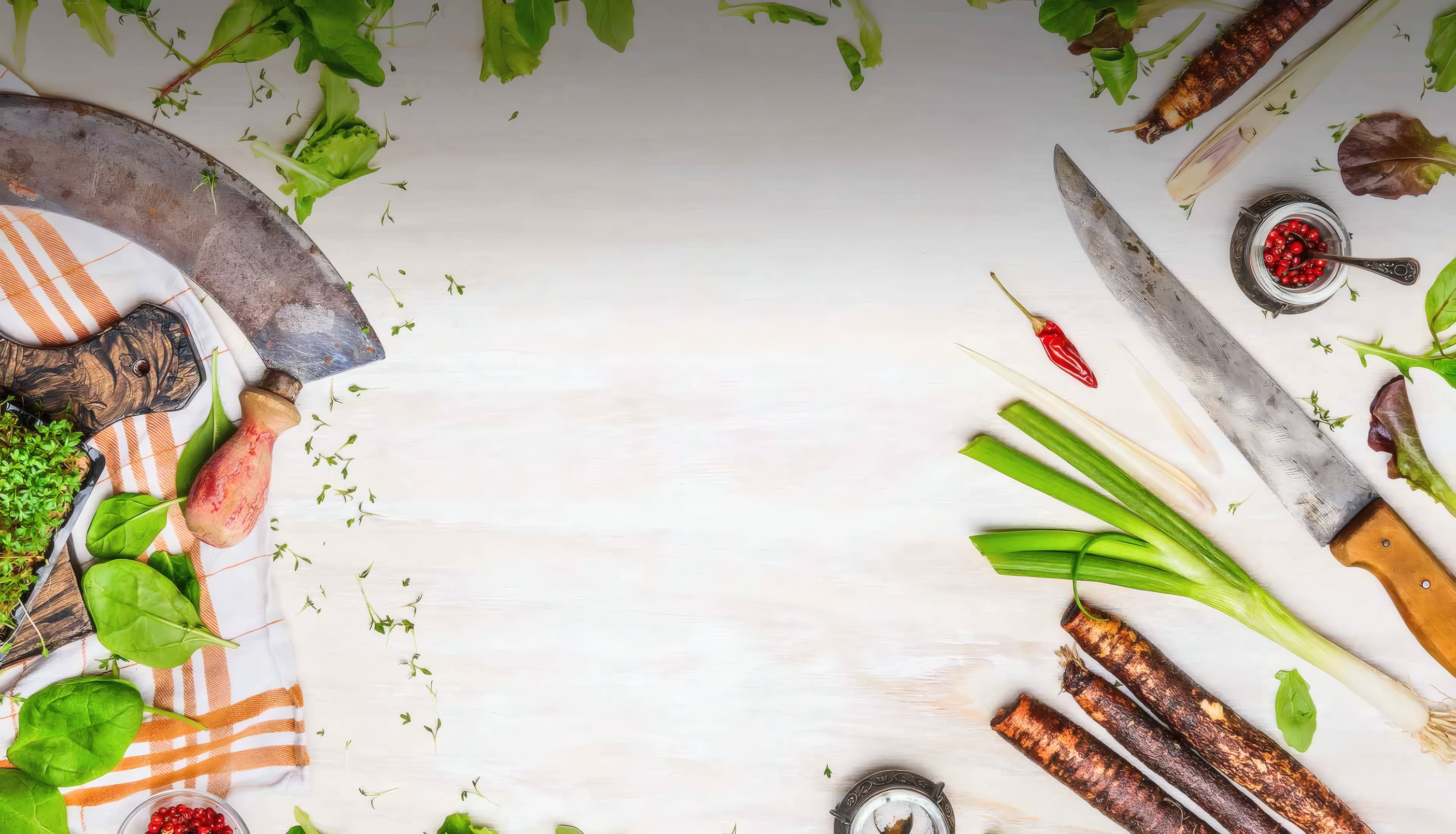 Herbs, knives and spring onions on a white kitchen table