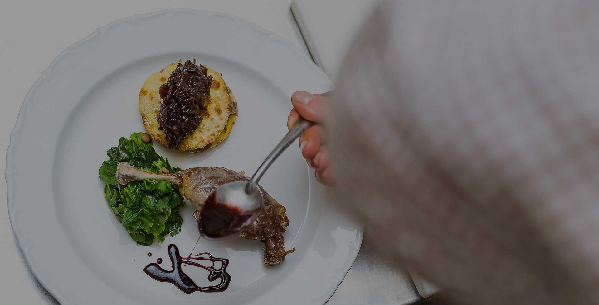 A hand lifting a plated dish from a grey table