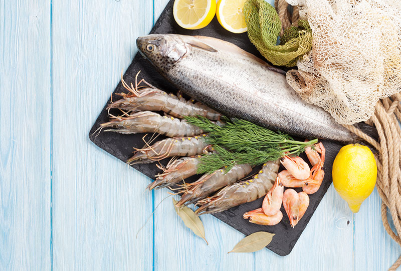 Fish, prawns and lemons laid out on blue boards